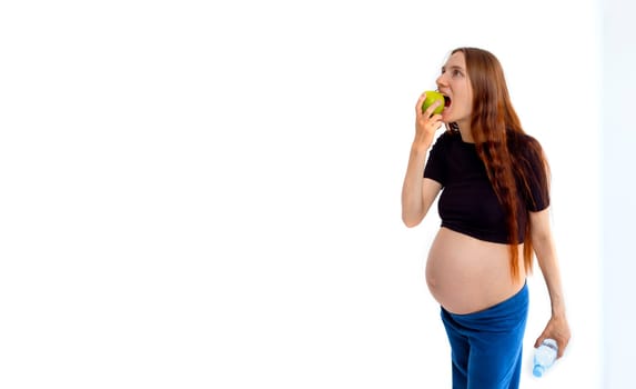 Pregnant woman propose apple for her belly copy space. Beautiful expectant lady having fresh snack, gray studio background. Healthy nutrition and pregnancy concept, copy space. Banner