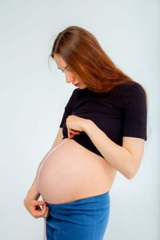 Pregnant woman measuring stomach with measuring tape. High quality photo