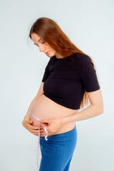 Pregnant woman measuring stomach with measuring tape. High quality photo