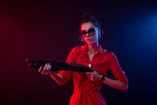 sexy hooligan girl in overalls with a shotgun on a dark background in neon light and haze copy paste
