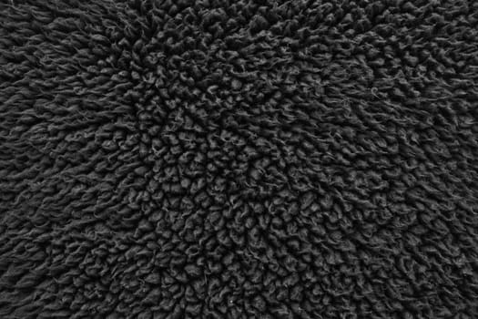 Faux fur black wool abstract pattern nature skin soft warm fluffy background dark artifical texture.