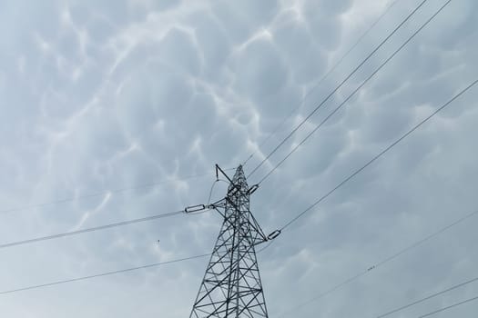 High voltage power line against a backdrop of billowing storm clouds. The forces of nature and modern electricity.