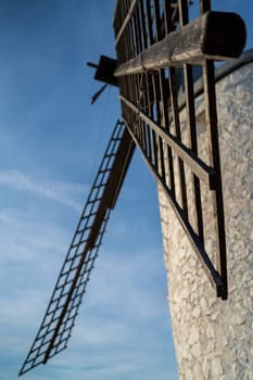 Bottom view of vintage windmill blades against blue sky, vertical composition