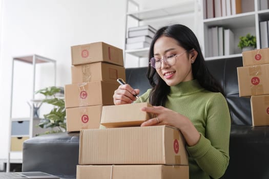 Startup small business entrepreneur SME, asian woman packing cloth in box. Portrait young Asian small business owner home office, online sell marketing delivery, SME e-commerce telemarketing concept