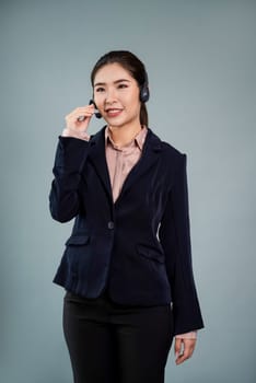 Attractive asian female call center operator with happy smile face advertises job opportunity on empty space, wearing a formal suit and headset on customizable isolated background. Enthusiastic