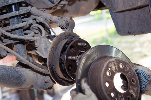 Gloved hands remove or slide the wheel rim onto the hub of the old car. In the garage, a man changes parts on a vehicle. Small business concept, car repair and maintenance service. UHD 4K.