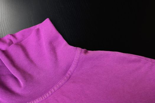 Part of pink sweater on wooden background close up