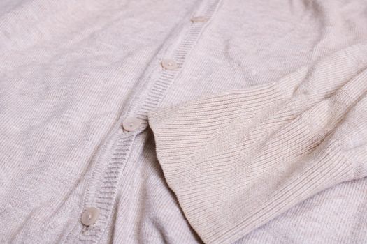 Buttons and sleeve on a beige sweater close up