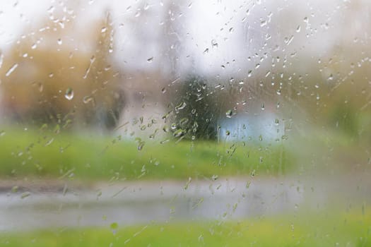 Raindrops on the glass of the window on the background of greenery