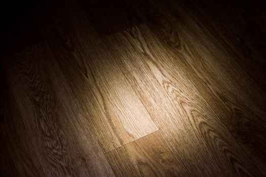 A ray of light on a wooden floor in the dark