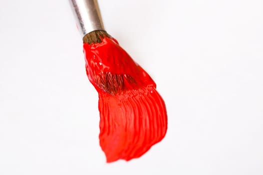 Brush with red paint on a sheet of paper