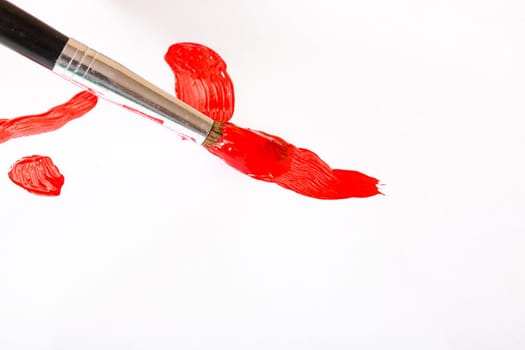 Brush with red paint on a sheet of paper