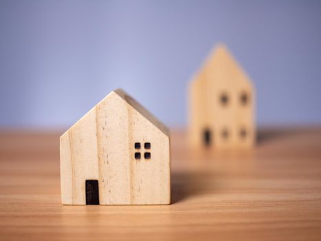 Two wooden model houses placed on a wooden table. with a white background