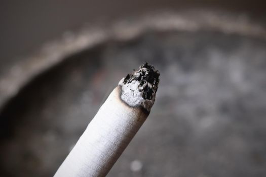 A lit cigarette and an ashtray close up