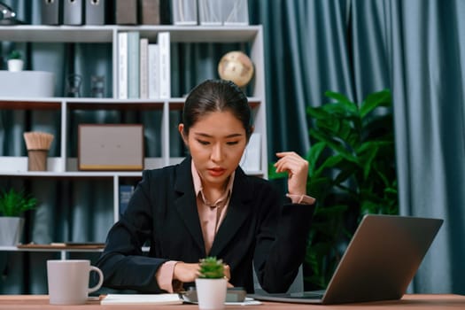 Young asian businesswoman is diligently working and taking notes in her modern office workspace, demonstrating professionalism as attractive and diligent office lady. Enthusiastic