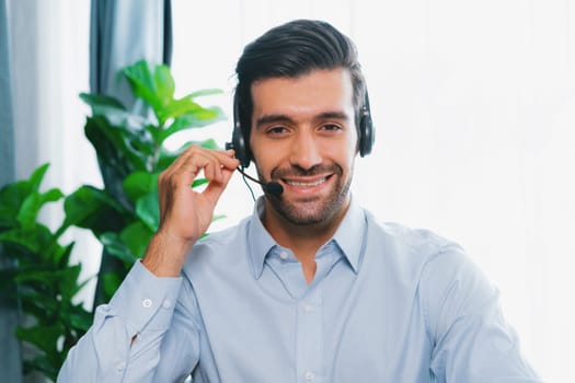 Male call center operator or telesales representative siting at his office desk wearing headset portrait. Customer service agent with smiling to camera on workplace. fervent