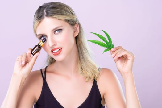 Alluring portrait of beautiful woman with perfect makeup hold green leaf, marijuan extracted bottle for skincare treatment product. Cannabis CBD oil for cosmetic and beauty in pink isolated background