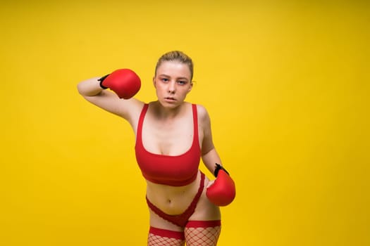 Seductive young and fit female fighter posing in gloves in a studio