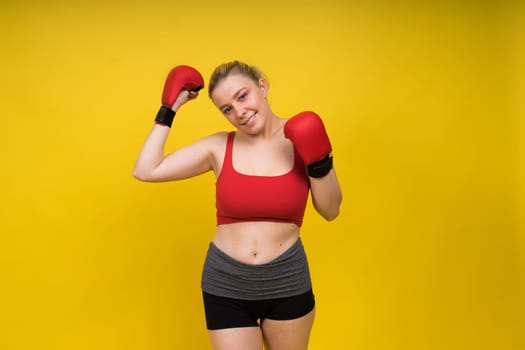 Seductive young and fit female fighter posing in gloves in a studio