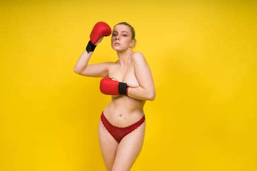 Seductive young and fit female fighter posing in gloves in a studio