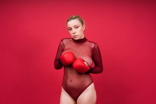 Seductive young and fit female fighter posing in gloves in a studio