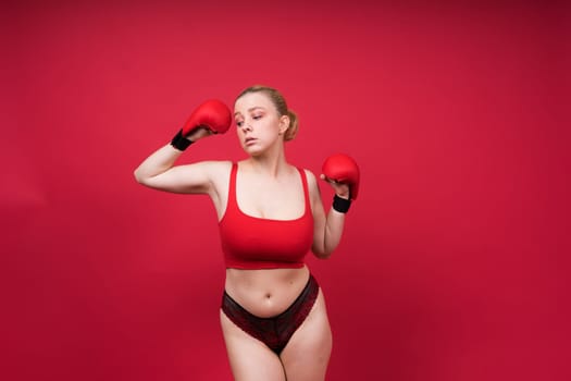 Seductive young and fit female fighter posing in gloves in a studio