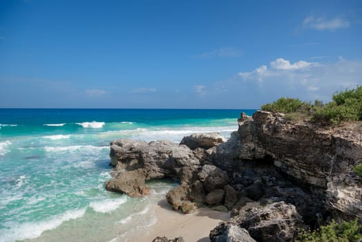 The coastline of the Caribbean Sea with white sand and rocks in Cancun.