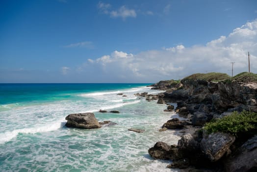 The coastline of the Caribbean Sea with white sand and rocks in Cancun.