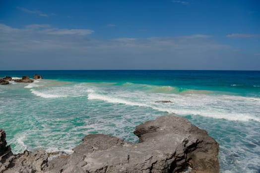 The coastline of the Caribbean Sea with white sand and rocks in Cancun.