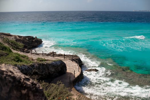 The coastline of the Caribbean Sea with white sand and rocks in Cancun.