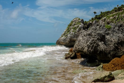 The coastline of the Caribbean Sea with white sand and rocks in Cancun.