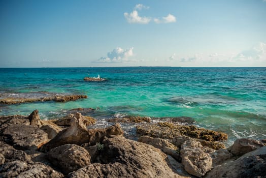 The coastline of the Caribbean Sea with white sand and rocks in Cancun.