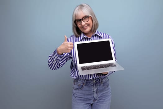 smiling 60s mature woman with gray hair with laptop mockup on bright studio background.