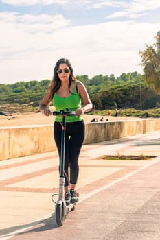 young latin girl on electric scooters having fun on city street on a sunny summer day. Outdoor portrait girl riding electric scooter in the park