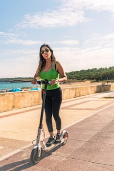 Woman riding electric scooter, happy and summer ride at tropical island beach resort for vacation. City, street and eco friendly transport, fun on escooter on holiday in mallorca,balearic island ,