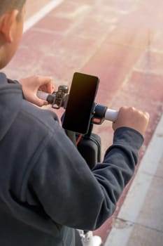 young man riding an electric scooter outdoors, looking at route on smartphone map application, sustainable transport concept, zero CO2 emission green energy