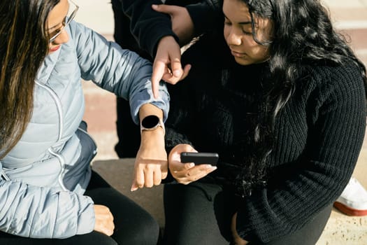 This stock photo shows three Latin people using their mobile devices and interacting with each other. The photo is cropped to focus on their hands holding the devices, as they chat and share content with one another. The image captures the modern and tech-savvy lifestyle of the Latin community, and can be used to illustrate topics such as social media, communication, technology, or cultural diversity. The picture is high-quality, with bright colors and clear details that will add a dynamic and engaging visual element to any project.