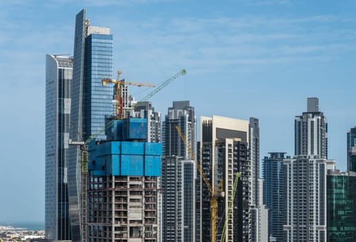 Cranes surround the construction of new tower for apartments along canal in Business Bay Dubai UAE