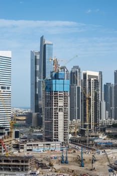 Cranes surround the construction of new tower for apartments along canal in Business Bay Dubai UAE