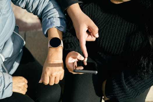 three Latin people using their mobile devices and interacting with each other. The photo is cropped to focus on their hands holding the devices, as they chat and share content with one another. The image captures the modern and tech-savvy lifestyle of the Latin community, and can be used to illustrate topics such as social media, communication, technology, or cultural diversity. The picture is high-quality, with bright colors and clear details that will add a dynamic and engaging visual element to any project.