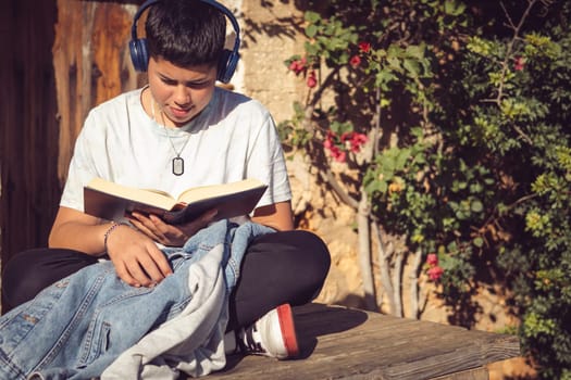 young man reading a book outside in the garden of the country house on a sunny winter's day