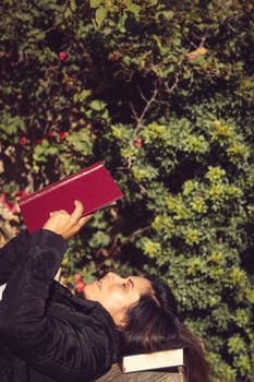 beautiful woman reading in garden, lying on wooden table takes vertical foreground copy space,