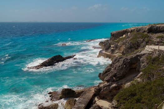 The coastline of the Caribbean Sea with white sand and rocks in Cancun.