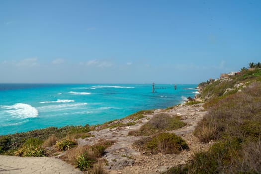 The coastline of the Caribbean Sea with white sand and rocks in Cancun.