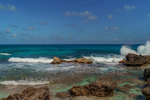 The coastline of the Caribbean Sea with white sand and rocks in Cancun.