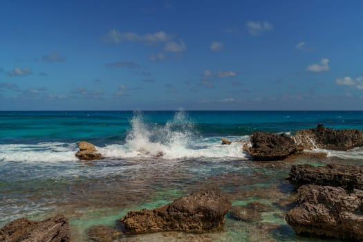 The coastline of the Caribbean Sea with white sand and rocks in Cancun.