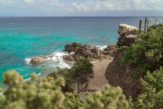 The coastline of the Caribbean Sea with white sand and rocks in Cancun.