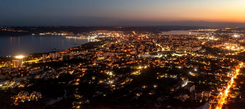 A panoramic aerial view of the city near sea at night. 