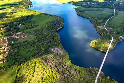 aerial view from a drone to a lake and a road between hills.