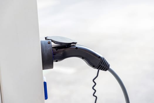 Closeup of charger plug to an electric vehicle from charging station. 